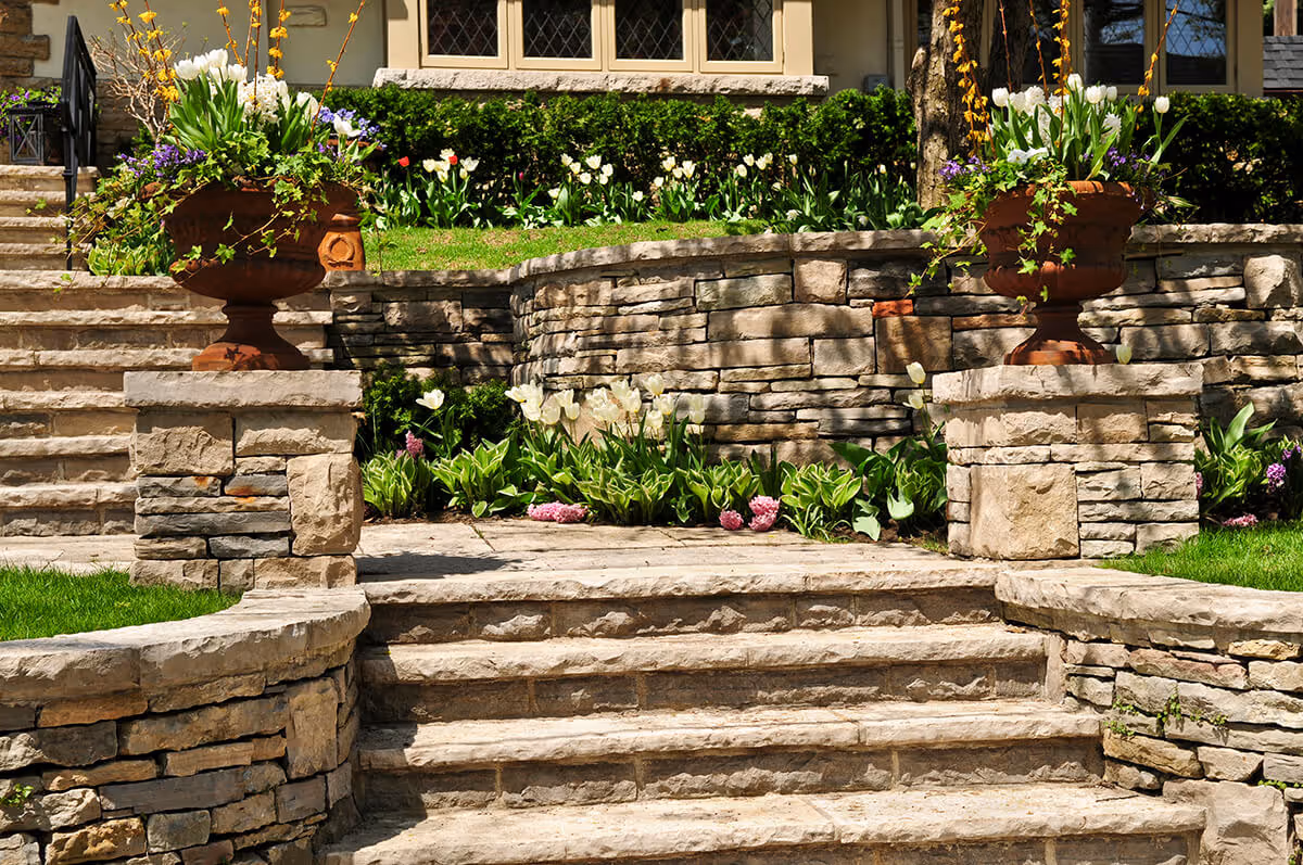 Photo of beautiful stone steps, and a stone retailing wall with lush landscaping surrounding it