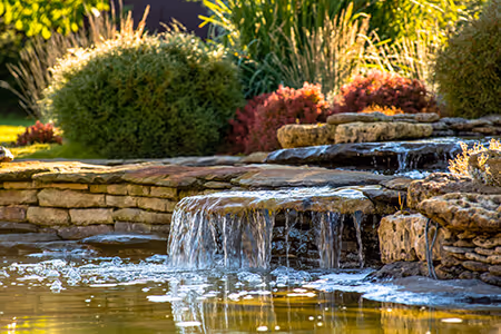 Photo of a beautiful rock water feature with bushes and landscaping around it